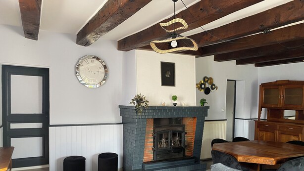 A cozy living room with a fireplace, a dining table, and a sofa.