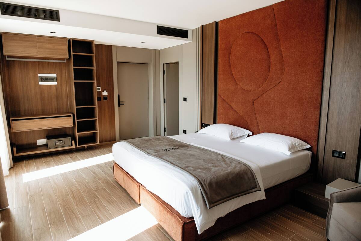 A modern bedroom with a large bed, built-in wardrobe, and a unique wall design.