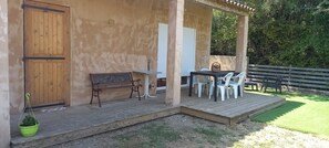 A wooden porch with a bench and a table with chairs, a wooden door, and a window with shutters. - Vacation Home (Montmeyan)
