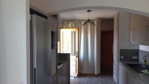 Uma cozinha pequena com geladeira, micro-ondas e luminária pendente.