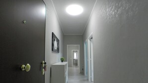 A hallway with a white console table, a door with a keyhole, and a ceiling light. - B&B - Il Terrazzo da Gregorio - Room 1 (Roma)