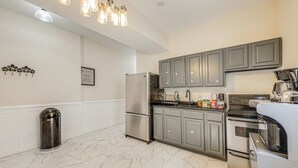 Una cocina moderna con gabinetes grises, electrodomésticos de acero inoxidable y piso de mármol.