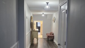 A hallway with a wooden floor, white walls, and a door on the right. - Downtown RVA Luxury Loft 3BR | Sleeps 6 | City View (Richmond)