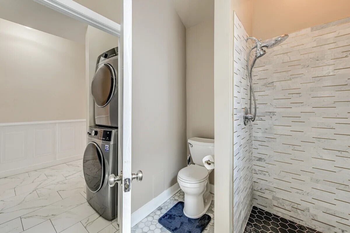 Une salle de bain équipée d’un lave-linge, de toilettes et d’une douche.
