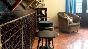 Una sala acogedora con barra, taburetes, sofá y una planta en maceta.