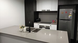 Eine moderne Küche mit einem Edelstahl-Kühlschrank, einem eingebauten Backofen und einer schwarzen Kaffeemaschine.