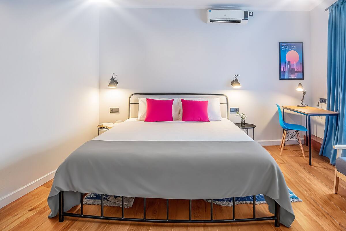 A neatly arranged bedroom with a bed, bedside tables, and a desk.