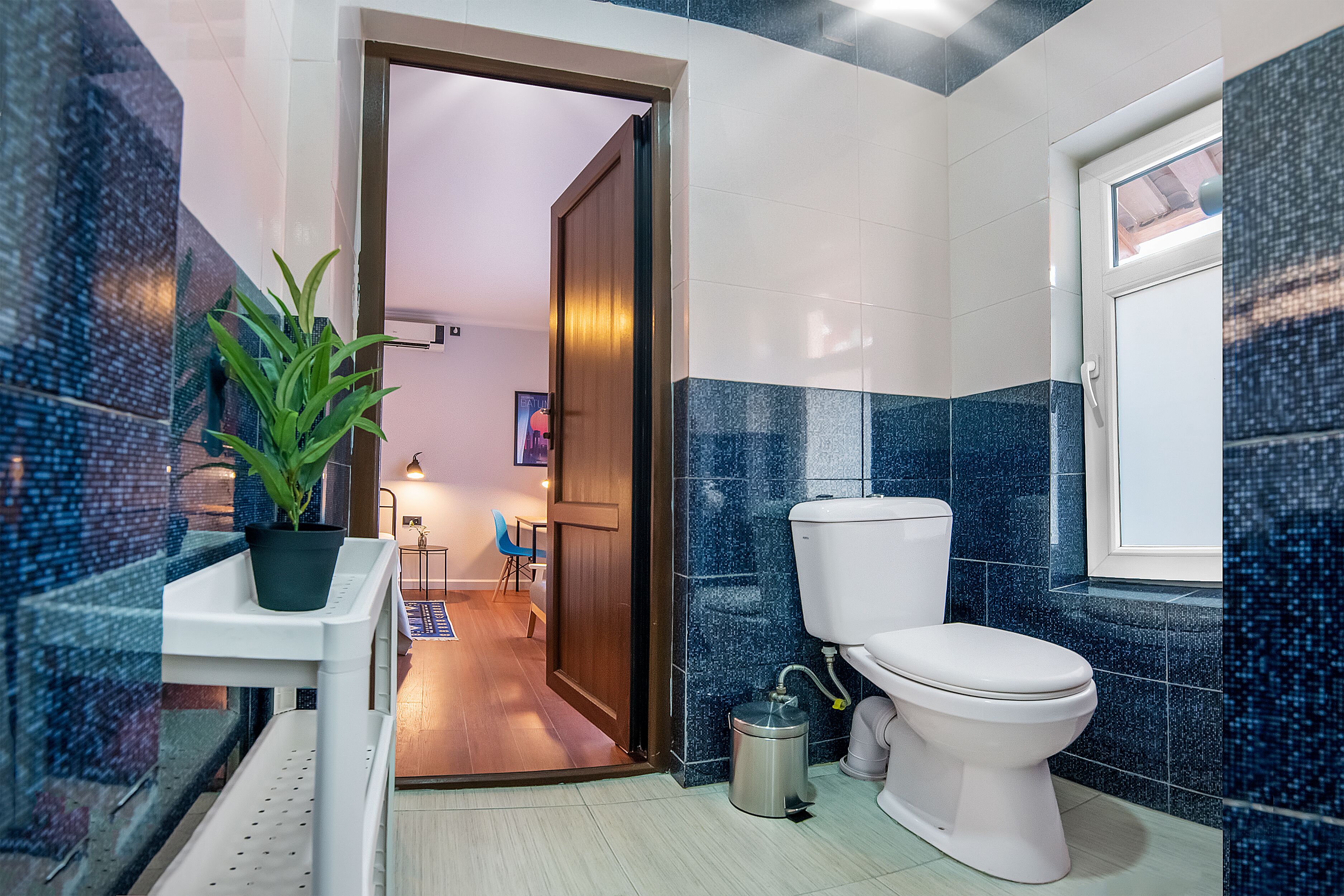Un baño con inodoro, lavamanos y planta en maceta.