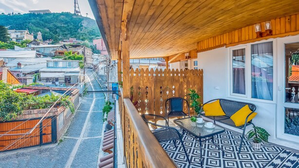 Un balcón con techo de madera, suelo estampado y zona de estar con mesa y sillas.