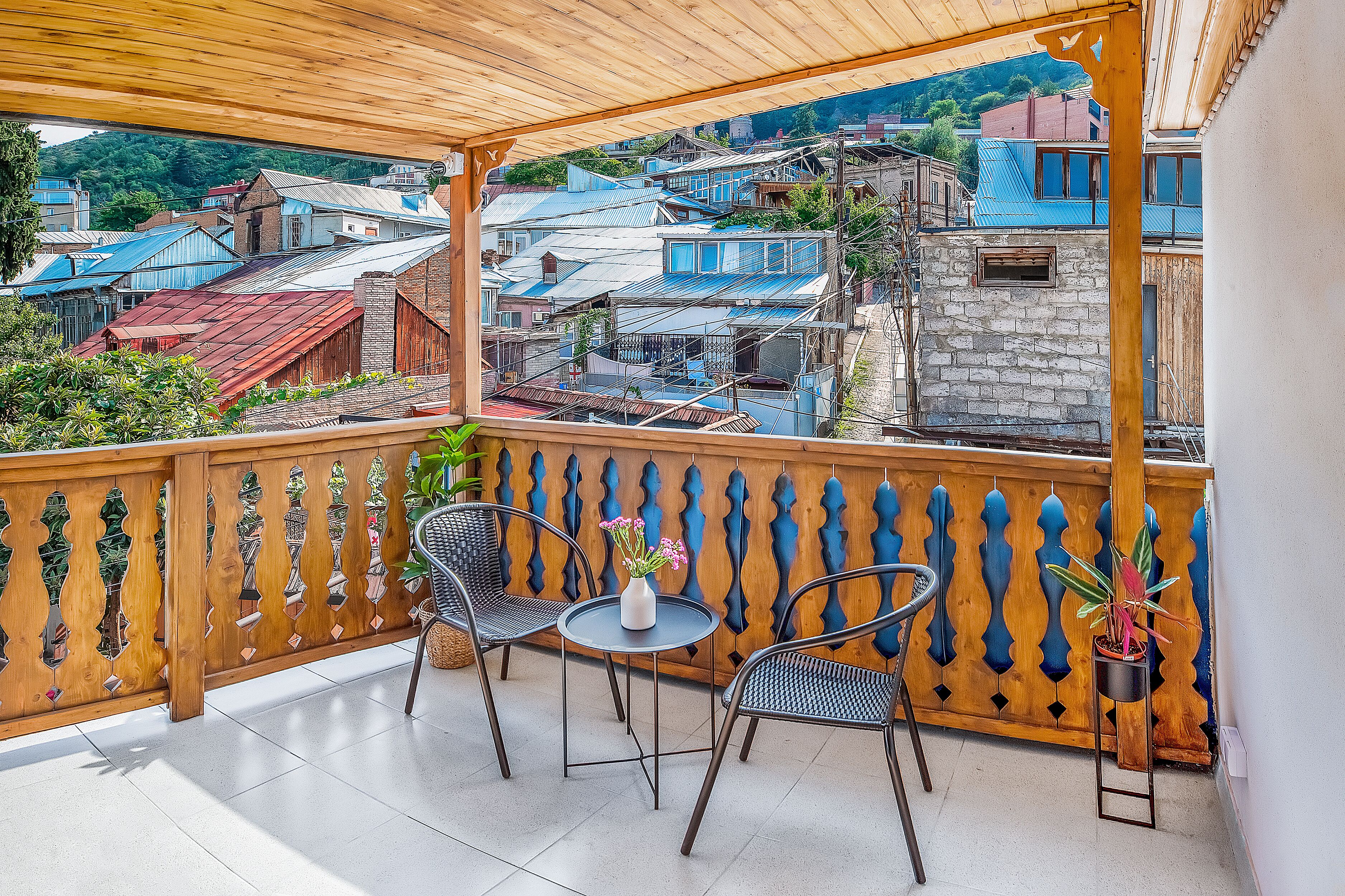 Un balcon avec deux chaises et une petite table, donnant sur un quartier résidentiel composé de différents immeubles.