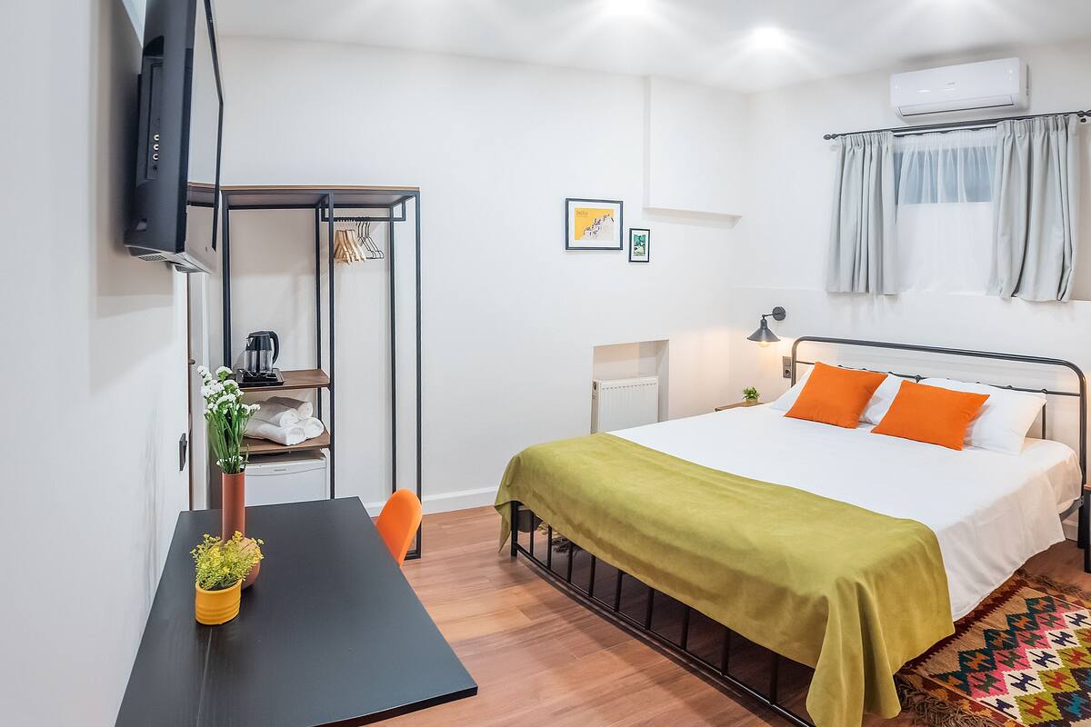 A neatly arranged bedroom with a bed, bedside table, and a small desk area.