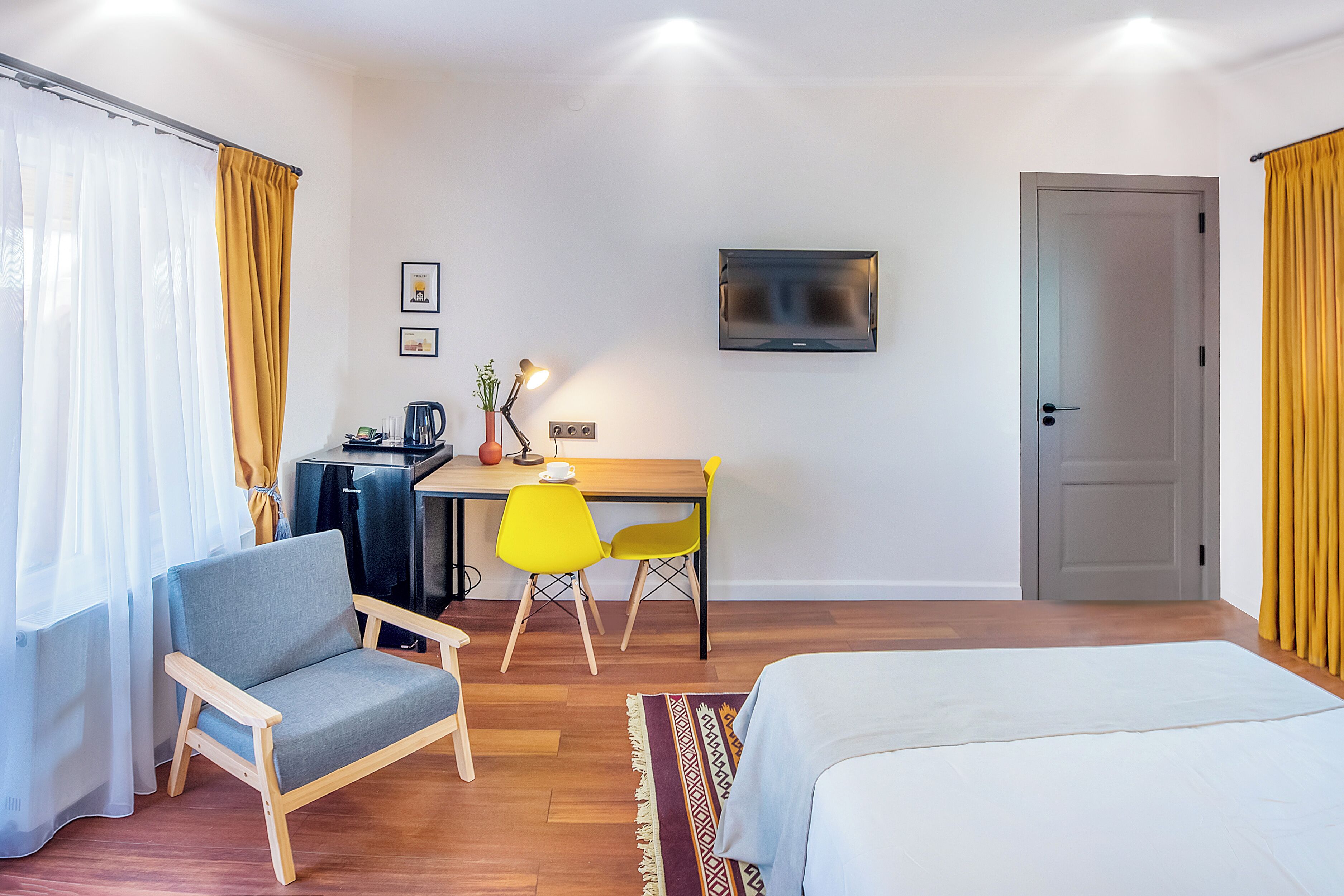 A hotel room with a bed, a desk with a chair, a television, and curtains.