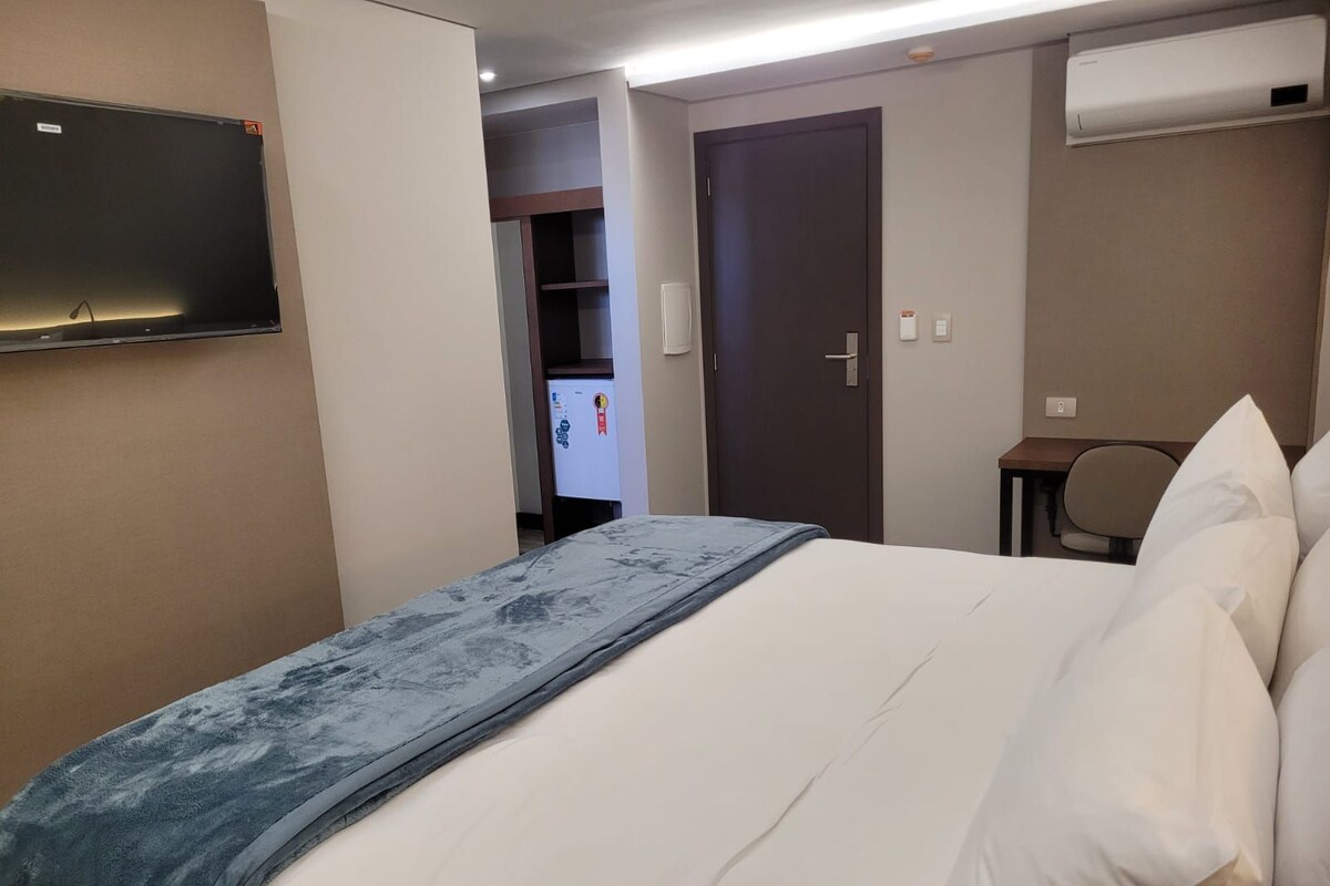 Une chambre d’hôtel équipée d’un lit, d’un téléviseur fixé au mur, d’un bureau et d’un appareil de climatisation.