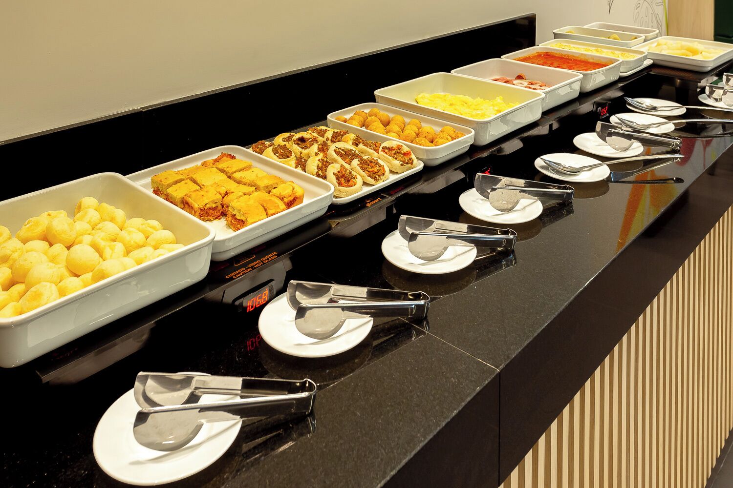 A buffet line with various food items and serving utensils.