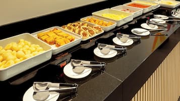 Una mesa de buffet con diversos alimentos y utensilios para servir.