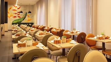 Un restaurante con varias mesas y sillas, cada conjunto con un mantel individual, un porta servilletas y una pequeña planta en maceta.