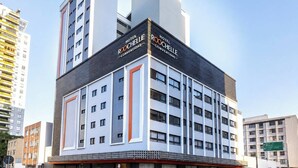 Un hôtel au design moderne, reconnaissable à son grand panneau « HÔTEL ROOCHETTE », à ses nombreux étages et à la vue dégagée qu’il offre sur l’environnement urbain.