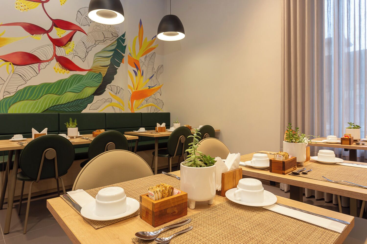 A restaurant with multiple tables, chairs, and a mural on the wall.