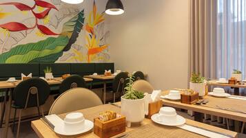 A restaurant with multiple tables, chairs, and a mural on the wall.