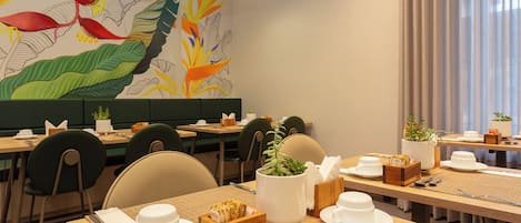 A restaurant with multiple tables, chairs, and a mural on the wall.