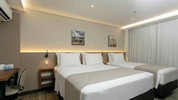 A hotel room with two beds, a desk, and a chair.