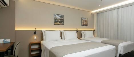 A hotel room with two beds, a desk, and a chair.