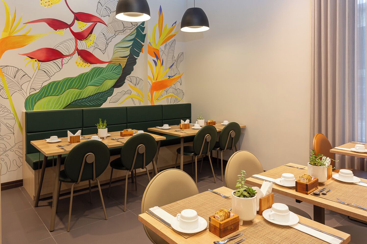 A restaurant with a green booth seating area, wooden tables, and chairs.