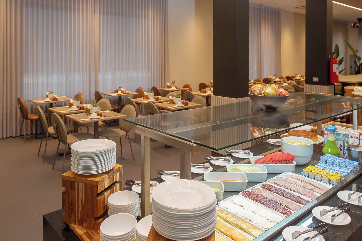 A buffet area with various food options, including meats, cheeses, and fruits, in a modern hotel setting.