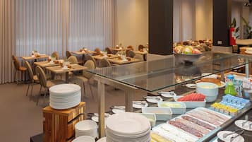 A buffet area with various food options, including meats, cheeses, and fruits, in a modern hotel setting.