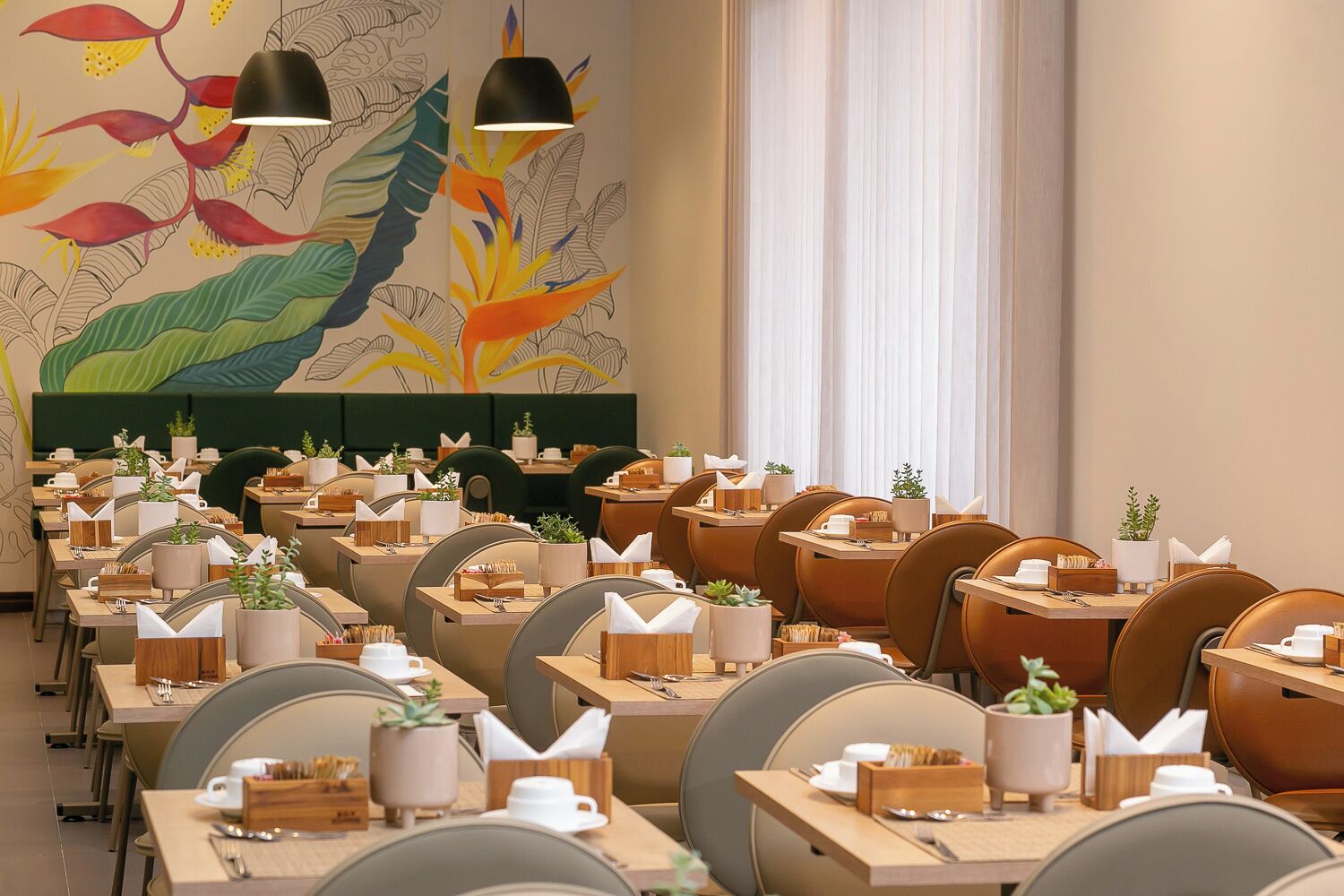 Een restaurant met meerdere tafels, elk voorzien van een plant, servet houder en bestek.