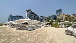 A beachside resort with sun loungers and umbrellas, surrounded by high-rise hotels.