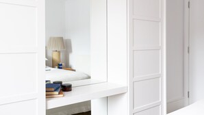 A white room with a bed, a bedside table with books and a lamp, and a white wardrobe. - The Masts 37 Dart Marina (Dartmouth)