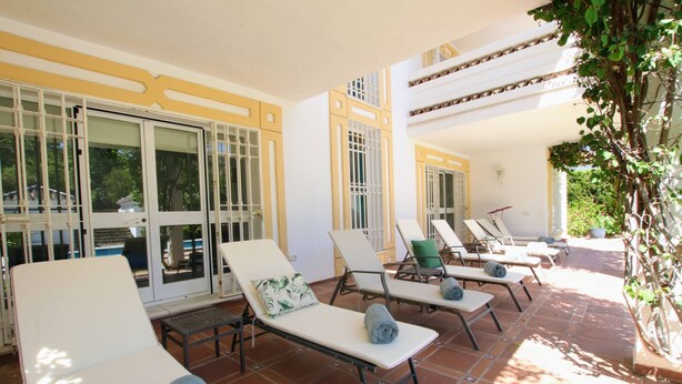 A sunlit outdoor lounge area with multiple white lounge chairs, some with towels, and a tiled floor. - Tess Villa Becerra in Alhaurin de la Torre (Alhaurin de la Torre)