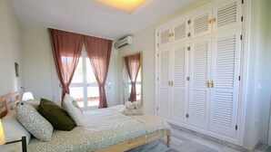 A bedroom with a bed, curtains, a wardrobe, and a mirror. - Tess Villa Becerra in Alhaurin de la Torre (Alhaurin de la Torre)