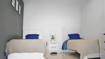 A bedroom with two beds, a nightstand with a lamp, and a dresser.