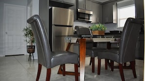 A modern kitchen with stainless steel appliances, a dining table with chairs, and a potted plant. - Elegant Apartment 10 min to Mercedes Outlets (Weslaco)
