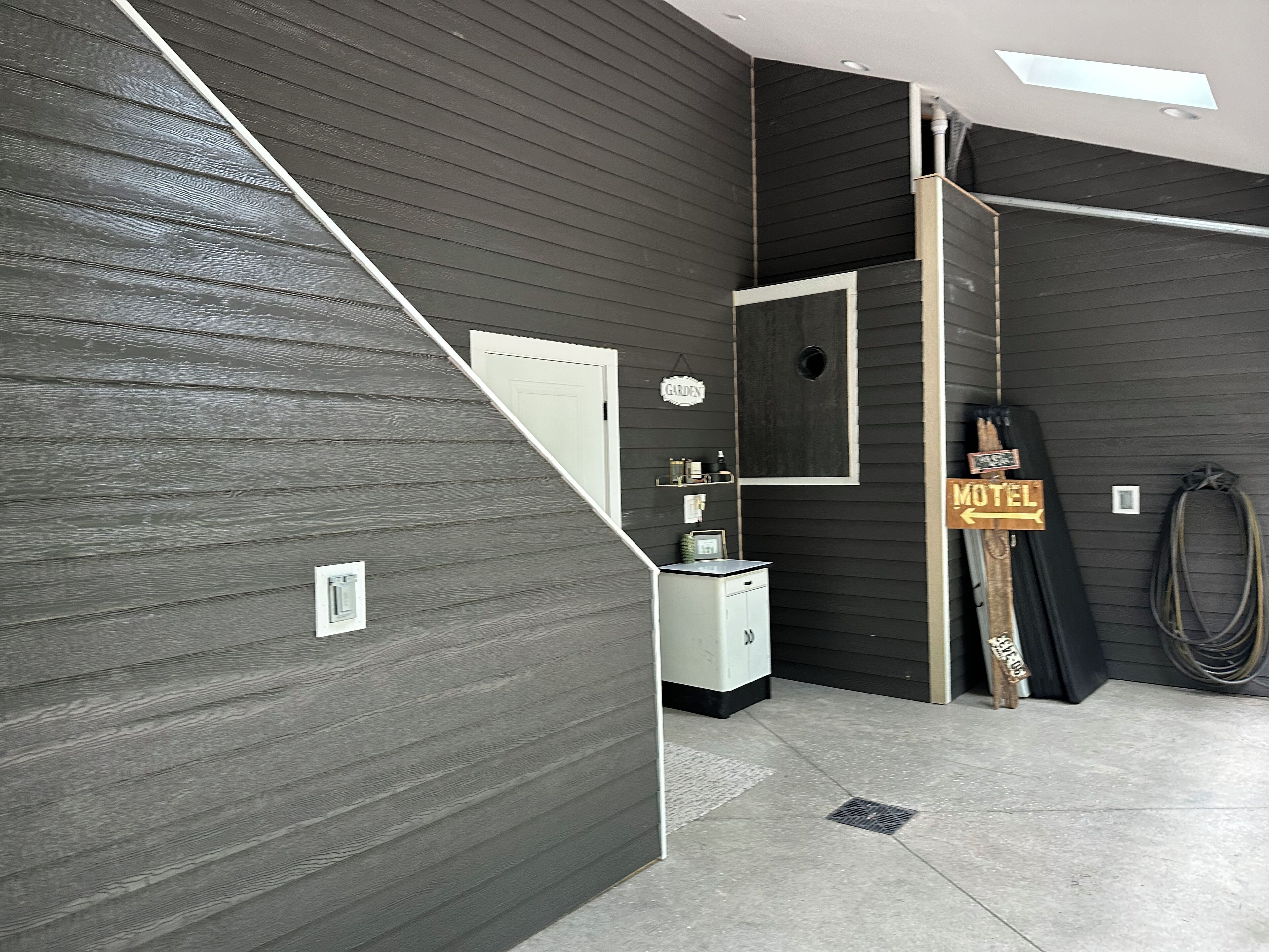 A room with dark wooden walls, a white door, a small white cabinet, and a neon sign indicating a motel.