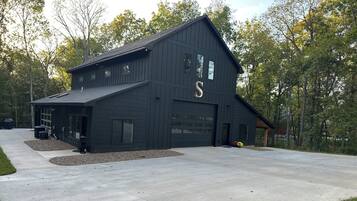 A large, dark wooden building with a garage and a driveway.