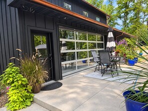 Una casa moderna con puerta de garaje, zona de estar al aire libre y plantas en macetas.