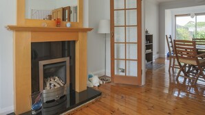 Ein großzügiges Wohnzimmer mit Kamin aus Holz, einem großen Spiegel und einer Glastür zu einem anderen Raum.