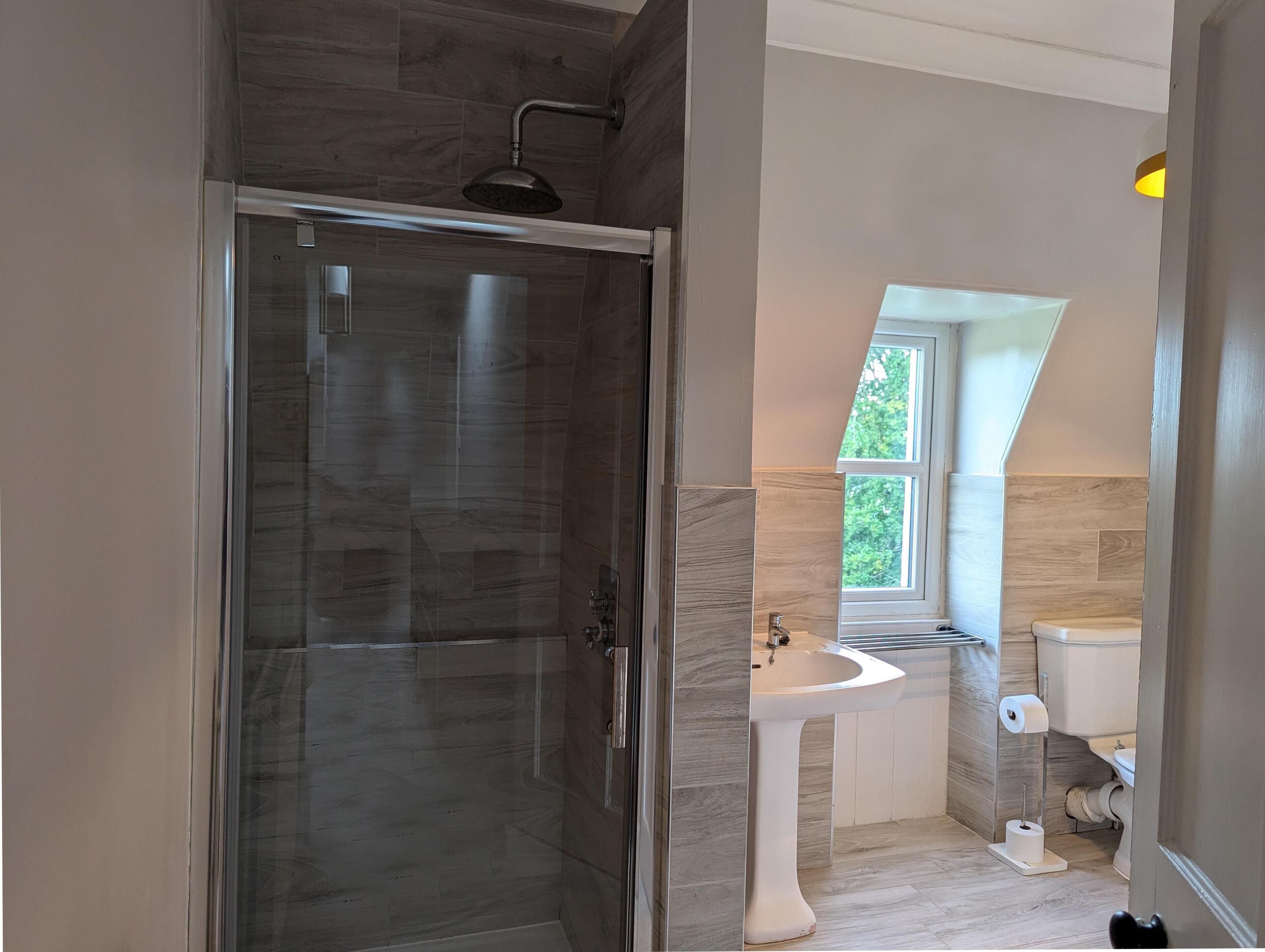 Une salle de bain moderne avec une douche à parois de verre, un lavabo sur colonne et des toilettes.