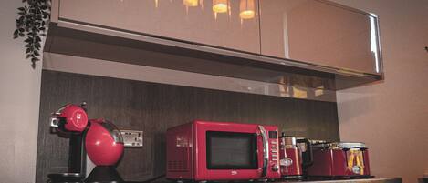 A kitchen with a microwave, a red appliance, and a coffee maker on the counter.