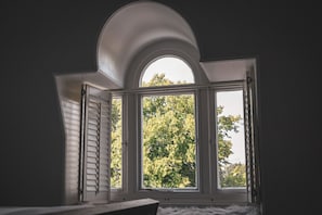 Une pièce dotée d’une grande fenêtre, d’une échelle et offrant une vue sur les arbres à l’extérieur.