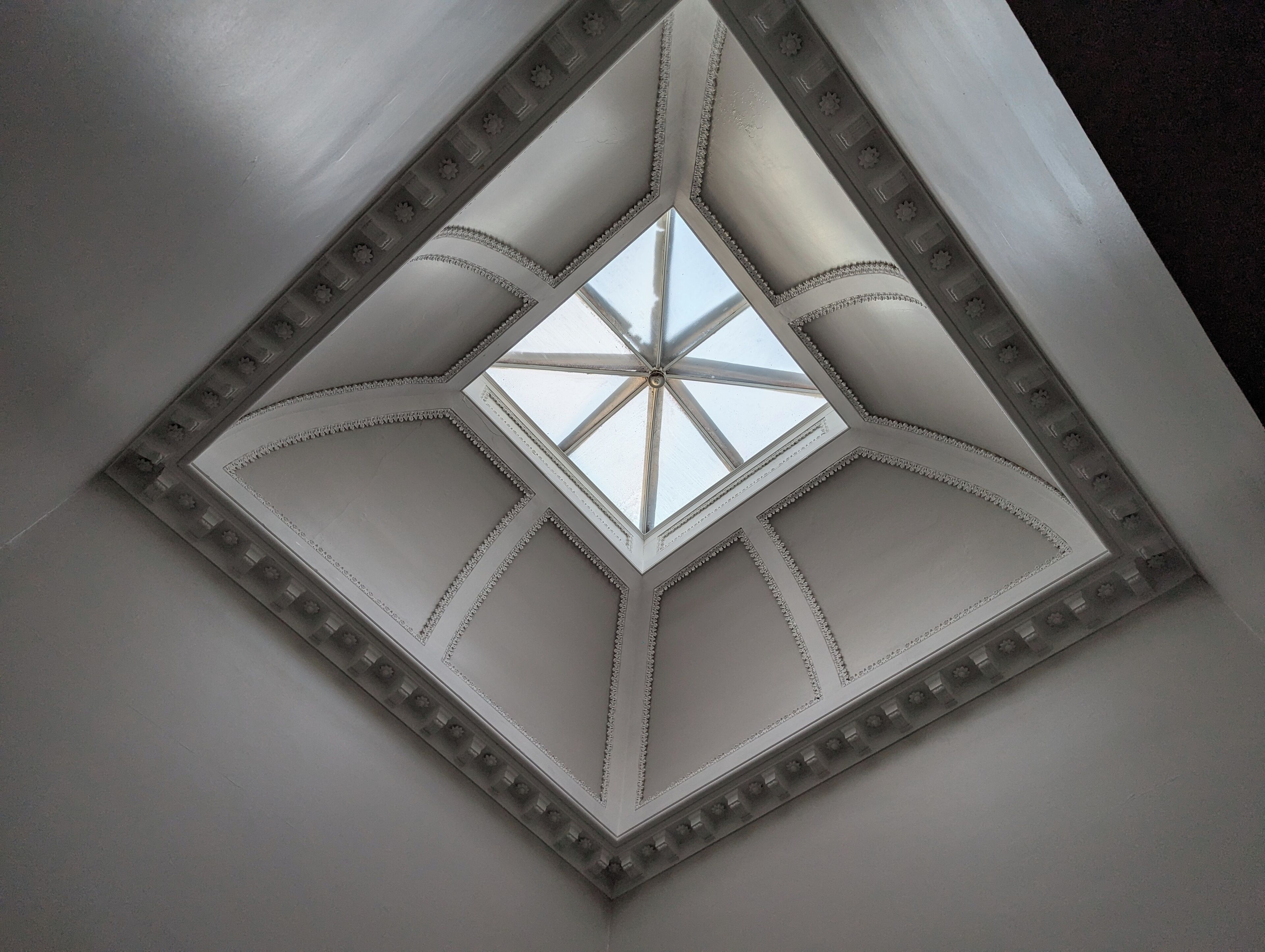 A skylight with a geometric design and decorative moldings.