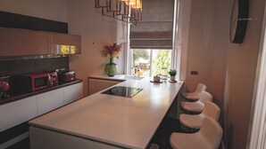 A modern kitchen with a central island, built-in appliances, and a window with a view. - Spacious 4 Bedroom Flat in Stirling (Stirling)