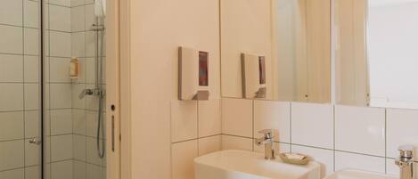A bathroom with a glass-enclosed shower, two sinks, and a large mirror.