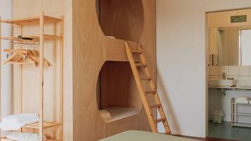 A bedroom with a bunk bed, wooden shelving unit, and a ladder leading to a loft.