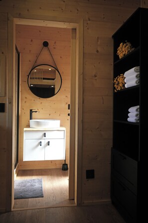 A wooden interior with a white sink, a mirror, and a black shelf with towels. - Quinta da Quinhas (Caminha)