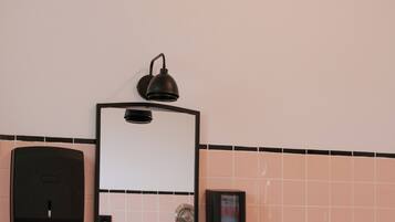 A bathroom with a white sink, a mirror, and a black wall-mounted light fixture.
