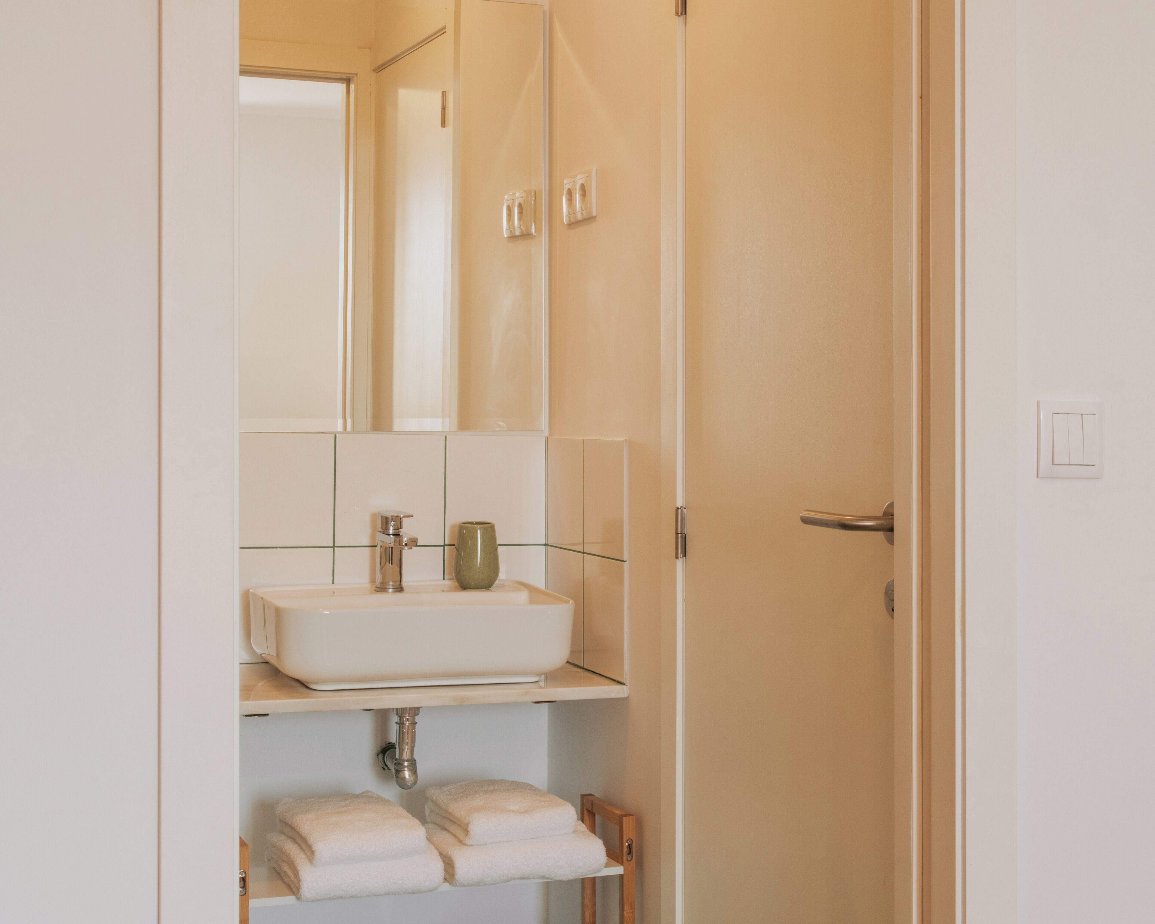A bathroom with a white sink, a mirror, and a towel rack.
